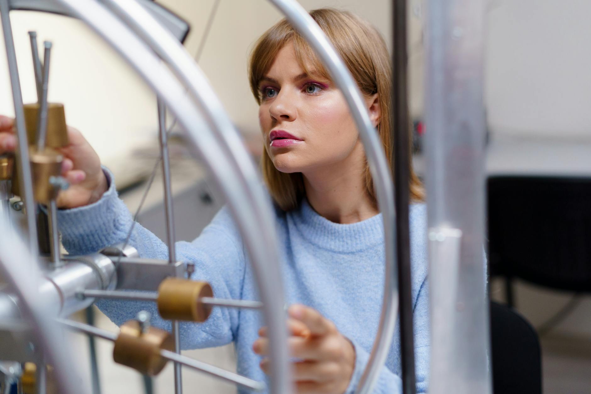 woman in blue sweater studying a metal object